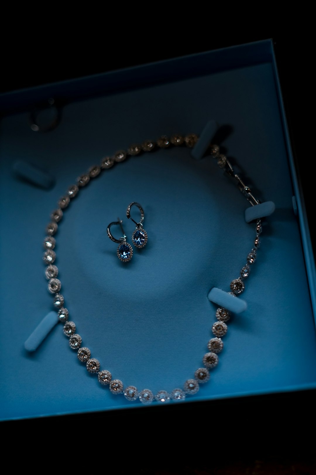 Diamond necklace and matching earrings resting inside a jewelry box.