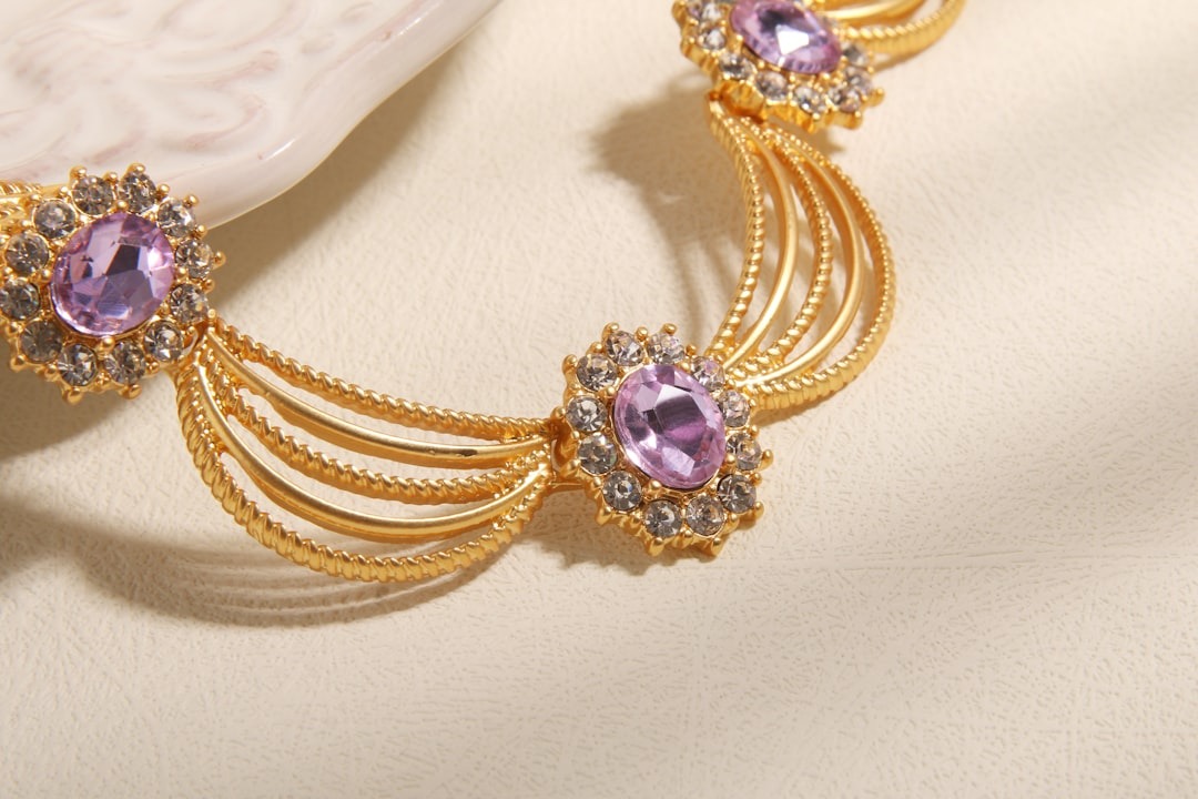 Ornate gold necklace with purple and clear gemstones.